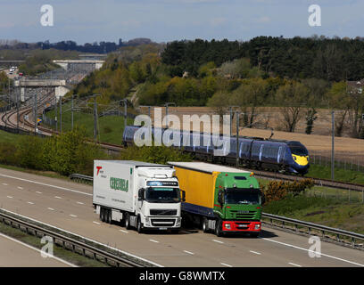 Un train Javelin à grande vitesse utilisant la ligne de chemin de fer HS1 passe le trafic de marchandises sur la M20 près d'Ashford dans le Kent. Banque D'Images