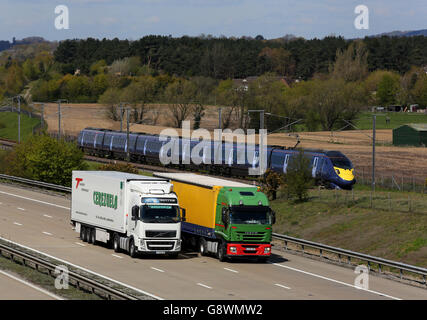 Un train Javelin à grande vitesse utilisant la ligne de chemin de fer HS1 passe le trafic de marchandises sur la M20 près d'Ashford dans le Kent. Banque D'Images