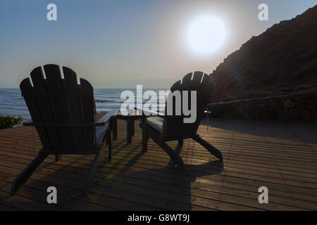 Deux chaises de détente en bois à côté d'une piscine à la plage. Banque D'Images