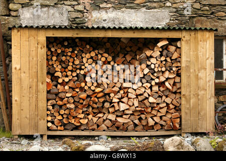 Hangar en bois ouverte magasin journal rempli de billes haché, prêt pour l'hiver. Lakeland Cumbria Lake District. UK Banque D'Images