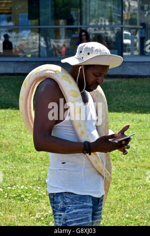 Un homme avec un grand python sur ses épaules la marche autour de la Baltimore Inner Harbor Banque D'Images