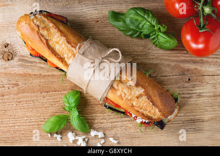 Baguette sandwich sous-marin végétarien tapissés avec aubergines grillées, poivre et fromage feta sur planche en bois foncé dessus Banque D'Images