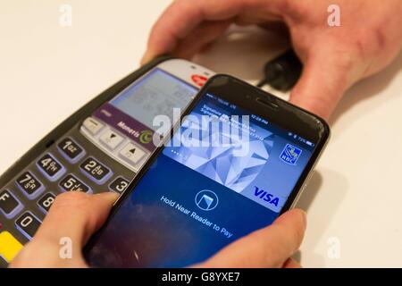 Kingston, Ontario, Canada. 16 mai, 2016. Un client utilise payer Apple app sur un iPhone à payer un article à aller dans un magasin d'informatique, Kingston (ON), le 16 mai 2016. © Lars Hagberg/ZUMA/Alamy Fil Live News Banque D'Images