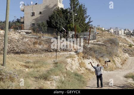 Bethléem, Cisjordanie, territoire palestinien. 1er juillet 2016. Un photographe palestinien réagit comme la police des frontières israélienne feu gaz lacrymogènes près d'une porte de barbelés de la partie israélienne controversée barrière de séparation entre la ville cisjordanienne de Bethléem et Jérusalem, après une tentative par les hommes palestiniens de passer en douce et se rendre dans la mosquée Al-Aqsa à Jérusalem à travers elle composé, à la suite d'une commande par la police israélienne a deux jours plus tôt pour empêcher les Palestiniens de traverser à prier sur le quatrième et dernier vendredi du mois du Ramadan en raison d'une hausse de la violence à l'emplacement, le 1 juillet Banque D'Images