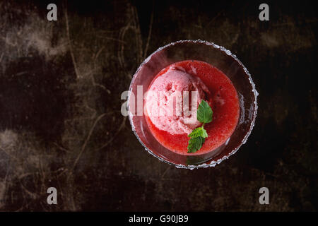 Verre à cocktail sucré de fraise dessert avec un sorbet, servi sur fond sombre avec de la menthe fraîche. Avec l'exemplaire de l'espace. Vue d'en haut Banque D'Images