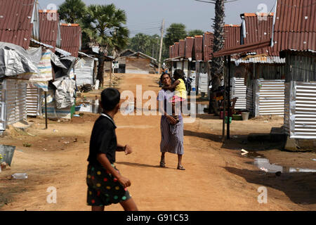 Une femme transporte son enfant à l'extérieur des refuges temporaires de Thirimadhu, Batticaloa, dans l'est du Sri Lanka, le mardi 29 novembre 2005. Le camp temporaire a été construit par des organismes de secours, après la destruction de plusieurs vitrages à proximité par le tsunami asiatique. La qualité et le taux de reconstruction du Sri Lanka après le tsunami ont été bien inférieurs à ce que l'on attendait malgré les fonds généreux accordés par les organismes d'aide. Voir PA Story DEATH Quake reconstruction. APPUYEZ SUR ASSOCIATION photo. Le crédit photo devrait se lire: Chris Young/PA Banque D'Images