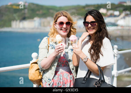 L'enseignement supérieur : deux étudiants de l'Université d'Aberystwyth femmes femmes de manger des glaces au soleil sur une chaude après-midi d'été ensoleillé Wales UK Banque D'Images