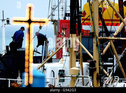 Les pêcheurs travaillent sous un crucifix éclairé au quai Kilmore à Wexford, le lundi 6 février 2006.Le bateau de pêche Rising Sun a quitté le port le 2005 décembre avant de sommer sur 10 kilomètres.Les experts en sauvetage tentent du soulever de la PRESSE de lit de mer Association photo.Le crédit photo devrait se lire comme suit : Niall Carson/PA. Banque D'Images