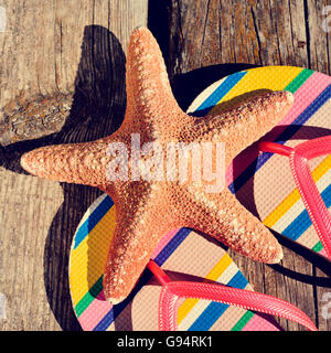 Libre d'une paire de tongs colorées et une étoile de mer sur une jetée en bois patiné Banque D'Images