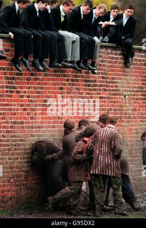 Les étudiants de l'Eton College assis sur le mur regardent le jeu par le haut Banque D'Images