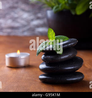 Black spa pierres avec de la menthe fraîche, l'aromathérapie, sur fond de bois. Banque D'Images