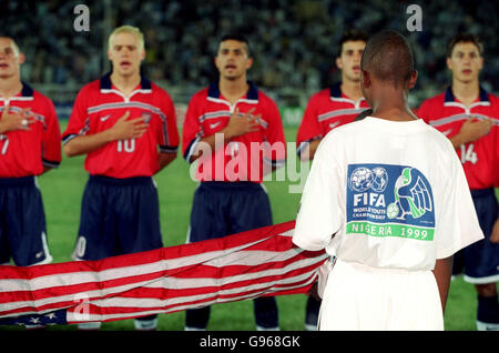 Football - Championnats du monde de la Jeunesse de la FIFA - Groupe E - Angleterre contre Etats-Unis.Le tam des États-Unis chante son hymne national en tant que garçon local portant un tee-shirt des Championnats du monde de la Jeunesse de la FIFA porte le drapeau américain Banque D'Images