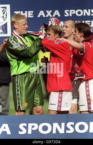 Peter Schmeichel, gardien de but de Manchester United (à gauche), célèbre en branlant les cheveux brycremed de David Beckham, sous la surveillance de ses coéquipiers Jaap Stam (deuxième à droite) et Gary Neville (à droite) Banque D'Images