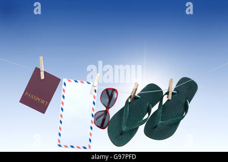 Vacances d'objets accrochés sur une ligne de lavage dont passeport, tongs, lunettes de soleil et enveloppe postale internationale Banque D'Images