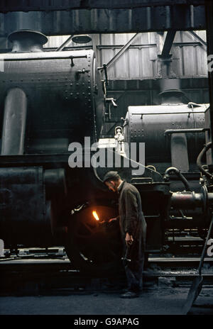 Un installateur complet avec lampe à pétrole et un marteau s'engage à réparer un ex-LMS Stanier 8F Catégorie 2-8-0 à Rose Grove depot, Burnley Banque D'Images