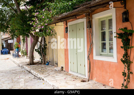 Ombragé Vue sur la rue, les vieux bâtiments traditionnels et de pavage en terrasses avec des fleurs et plantes, Fiskardo, Kefalonia, Grèce Banque D'Images