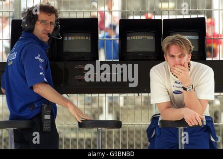 (G-D) le patron de l'équipe Alain Prost et le pilote Nick Heidfeld attendent sur le mur de la fosse pour que la voiture de Heidfeld soit préparée Banque D'Images