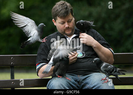 Un homme est couvert par les pigeons comme il les nourrit à St Stephen's Green à Dublin. Banque D'Images