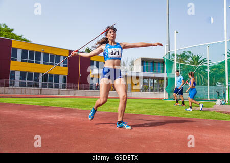 Young woman throwing javelin sur une piste d'athlétisme Banque D'Images