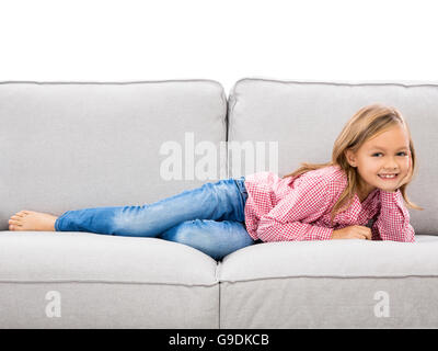 Petite fille à la maison couché sur un divan Banque D'Images