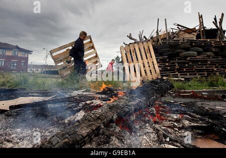 Les jeunes fidèles construisent un feu de camp sur la route Shankill à Belfast. Ce sera l'un des centaines de feux de joie qui seront mis à feu ce soir dans toute l'Irlande du Nord, signalant le début de la plus grande journée de marche dans le calendrier de l'ordre Orange. Banque D'Images