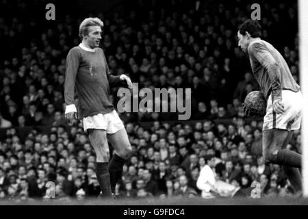 Denis Law (l) de Manchester United attend le gardien de Leicester City Gordon Banks (r) pour faire un coup de pied sur le terrain Banque D'Images