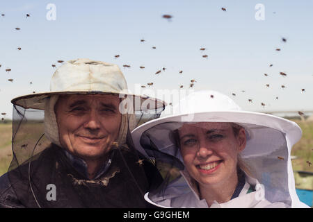 Portrait horizontal de deux apiculteurs, père et fille, entourée d'abeilles swarmming Banque D'Images