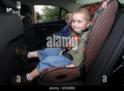 Sam Davies, trois ans, (près de l'appareil photo) dans son siège de voiture orienté vers l'avant. Banque D'Images