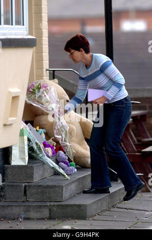 Une femme dépose des fleurs à la porte de la Rocket public House à Stevenson Drive, dans la région de New Park à Leicester, où une jeune fille de cinq mois a été malléée par deux chiens de garde. Banque D'Images