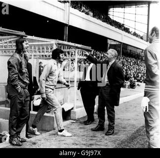 Charlie George (l) d'Arsenal et Bill Shankly (r), le directeur de Liverpool, rient la tête tandis que le commentateur Jimmy Hill (c) émerge dans une piste bleu ciel pour prendre le contrôle de l'homme de ligne, qui s'était lésé. Un message a été diffusé sur le système de sonorisation demandant à un arbitre qualifié de prendre la relève de l'homme de ligne, et Hill était la seule personne à se présenter Banque D'Images