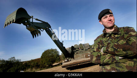 Le Caporal Andrew Jones se trouve à côté du nouveau cheval de Troie de l'Armée de terre à bord d'un char d'ingénieurs lourdement blindé, dans la zone d'entraînement militaire de Bovington, à Dorset. Banque D'Images