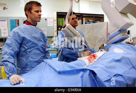 Le cardiologue consultant Dr Anthony Mathur (à droite) et le registraire Julian Strange effectuent une angiographie, une opération cardiaque exploratoire au London Chest Hospital, après le lancement de la campagne d'affiches de la British Heart Fdoundation, qui encourage le public à téléphoner au 999 d'abord s'ils soupçonnent qu'ils ont une crise cardiaque. Banque D'Images