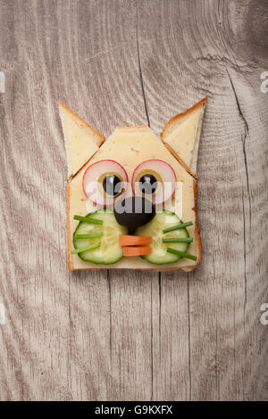 Chat drôle fait de pain grillé et fromage sur fond de bois Banque D'Images