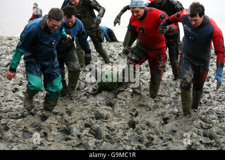 Un concurrent est entraîné vers la ligne d'arrivée lorsqu'il participe à la course Mad Maldon Mud 2006 qui s'est tenue à Maldon, dans l'Essex. Banque D'Images