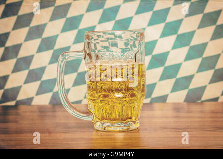 Beer mug sur planche de bois en face du drapeau bavarois Banque D'Images