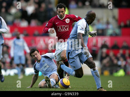 Ryan Giggs (au centre) de Manchester United passe devant Joey Barton (l) de Manchester City et Hatem Trabelsi lors du match Barclays Premiership à Old Trafford, Manchester. Banque D'Images