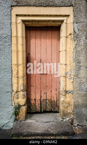 Une vieille porte en bois en décomposition cottage en pierre cadre. Banque D'Images