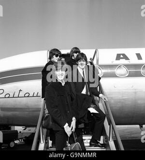 Les Beatles sur les marches de l'avion avant de quitter l'aéroport de Londres pour Paris au début de la visite continentale qui comprendra la France, l'Italie et l'Espagne. En face, George Harrison (à gauche) et Paul McCartney. Arrière, John Lennon (gauche) et Ringo Starr. Banque D'Images