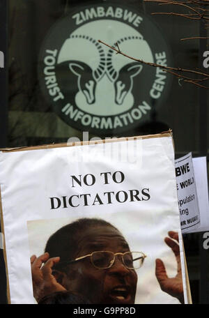 Un écriteau montrant le visage de Robert Mugabe et lisant « non aux dictateurs » est vu avant le panneau pour le centre d'information touristique du Zimbabwe, lors d'une manifestation contre la dictature de Robert Mugabe au Zimbabwe, devant l'ambassade du Zimbabwe à Londres. Banque D'Images