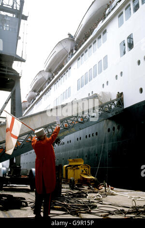 Le drapeau ondulant no 1 de Grande-Bretagne, M. Ken Bailey, dans son chapeau haut et ses queues rouges distinctifs, alors que les dernières troupes embarquèrent dans le QE2 avant que le navire-drapeau de Cunard navigue de Southampton pour l'Atlantique sud en tant que transporteur de troupes à la force opérationnelle des Falklands. Banque D'Images