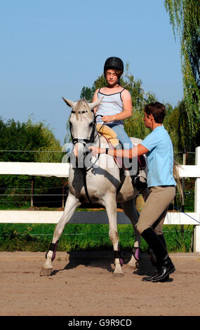 Fille sur le poney / Cheval allemand professeur d'équitation, sidepass, casque, manège Banque D'Images