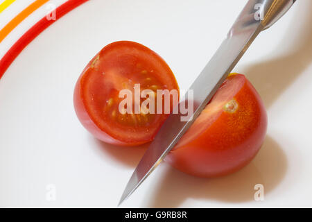 Une seule tomate rouge ouvert en tranches avec un couteau Banque D'Images