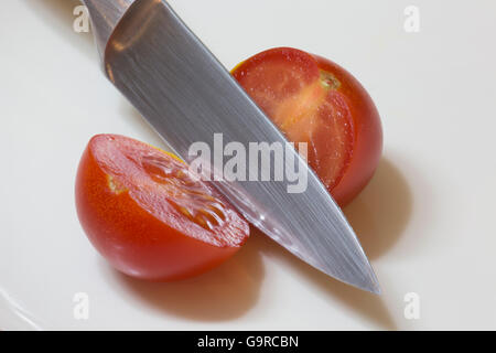 Une seule tomate rouge ouvert en tranches avec un couteau Banque D'Images