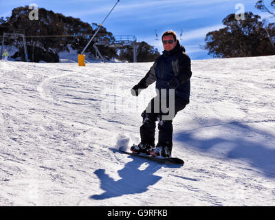 Heureux snowboarder glisse vers le bas de la voie en montagnes de neige station de ski de Perisher Valley, le parc national de Kosciuszko. Banque D'Images