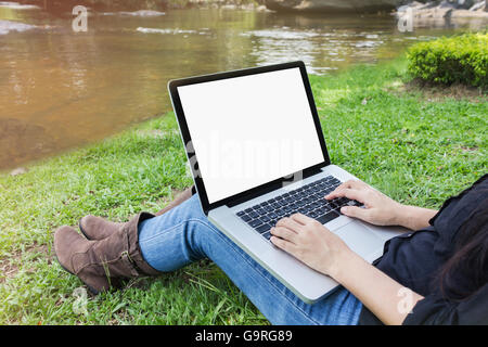 Ordinateur portable avec écran vide girl sitting on grass field at Riverside, fille ou femme surf internet en vous détendre humeur des ri naturel Banque D'Images