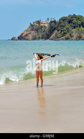 Young woman in bikini holding un paréo dans le vent / Koh Lanta, Thaïlande, Asie Banque D'Images