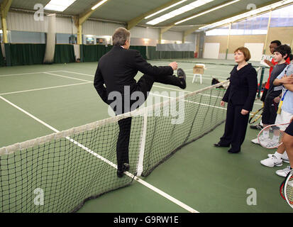 Tessa Jowell, secrétaire à la culture, regarde le Premier ministre britannique Tony Blair croiser un filet de tennis tout en parlant avec des jeunes à la Westway Sports Academy de Londres. Banque D'Images