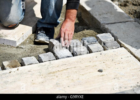 Détail avec les travaux d'installation de cobblestone par un maçon Banque D'Images