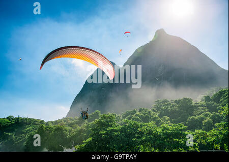 Parapentiste passe le long de la verdure de Misty Mountain Pedra da Gavea sur sa façon d'atterrir à São Conrado Beach à Rio de Janeiro Banque D'Images