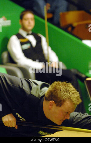 Shaun Murphy d'Angleterre à la table comme Matthew Stevens du pays de Galles regarde depuis sa chaise pendant le quart de finale de match aux Championnats du monde de Snooker au Crucible Theatre, Sheffield. Banque D'Images